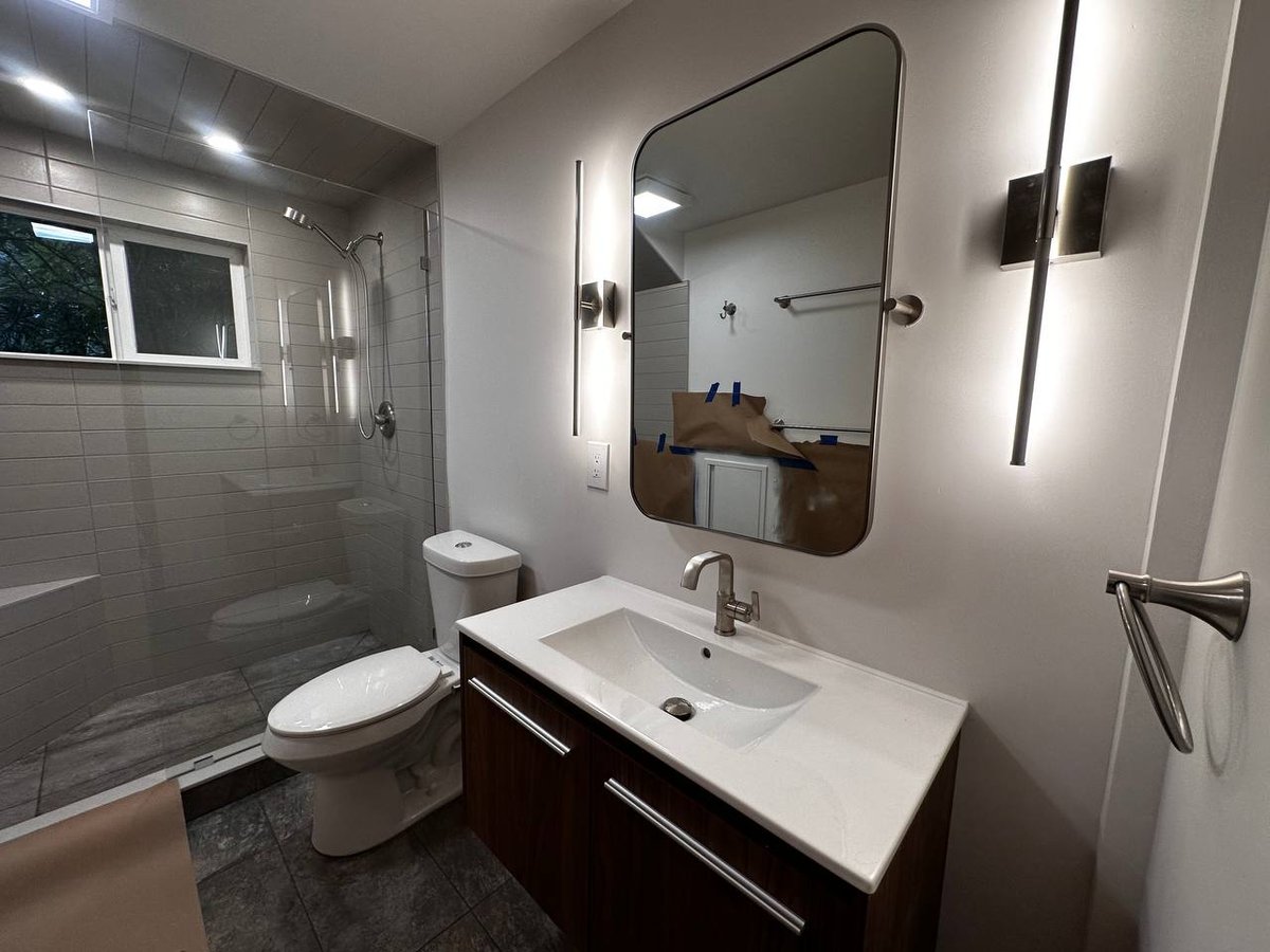 Master bathroom after — finished walk-in shower, vanity, modern lighting