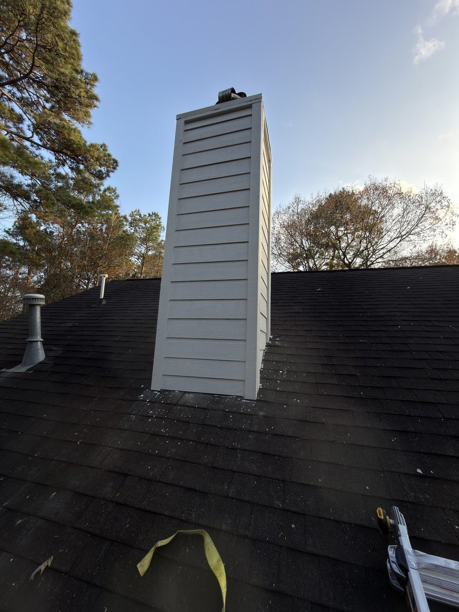 Chimney exterior after — new white HardiePlank siding, primed and painted