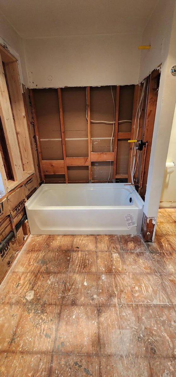 Bathroom before — new tub installed, walls demo'd to studs