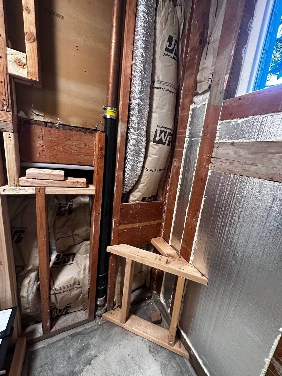 Master bath before — exposed framing, copper rough-in