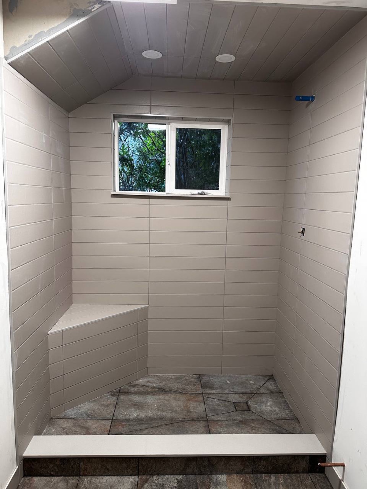 Tiled walk-in shower with bench and window